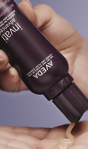 A person dispenses a creamy product from a tube labeled "Aveda Invati Advanced" onto their palm. | Anaala Salon and Spa, Madison WI