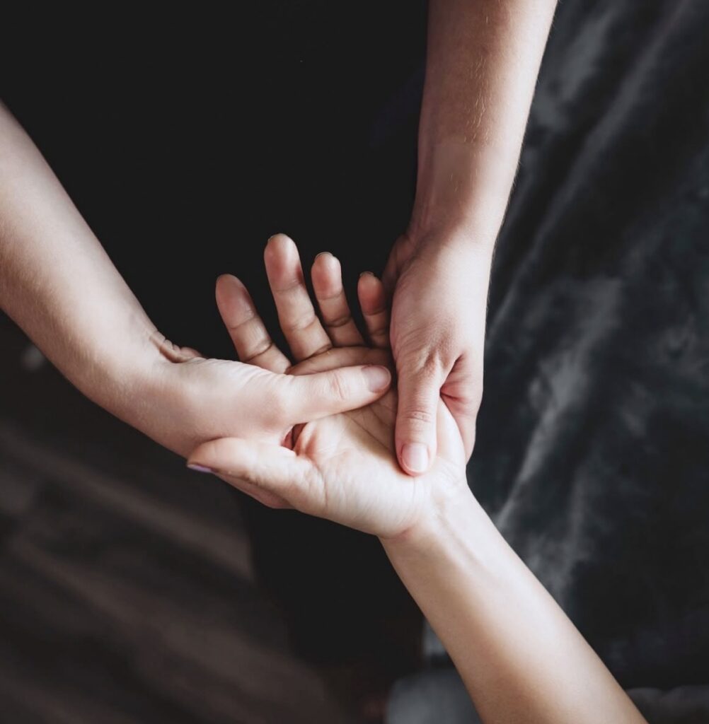 Two hands are shown as one person presses their thumb into the palm of another's hand, suggesting a relaxing hand massage—just one of many soothing treatments offered at the best salon in Madison WI. | Anaala Salon and Spa, Madison WI