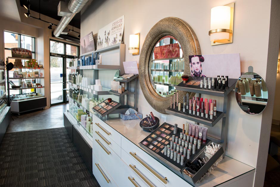 Cosmetics display in a well-lit store, featuring makeup products, skincare items, and a round mirror on the wall. Shelves and counters are neatly organized—perfect for those seeking the best facial in Madison WI. | Anaala Salon and Spa, Madison WI